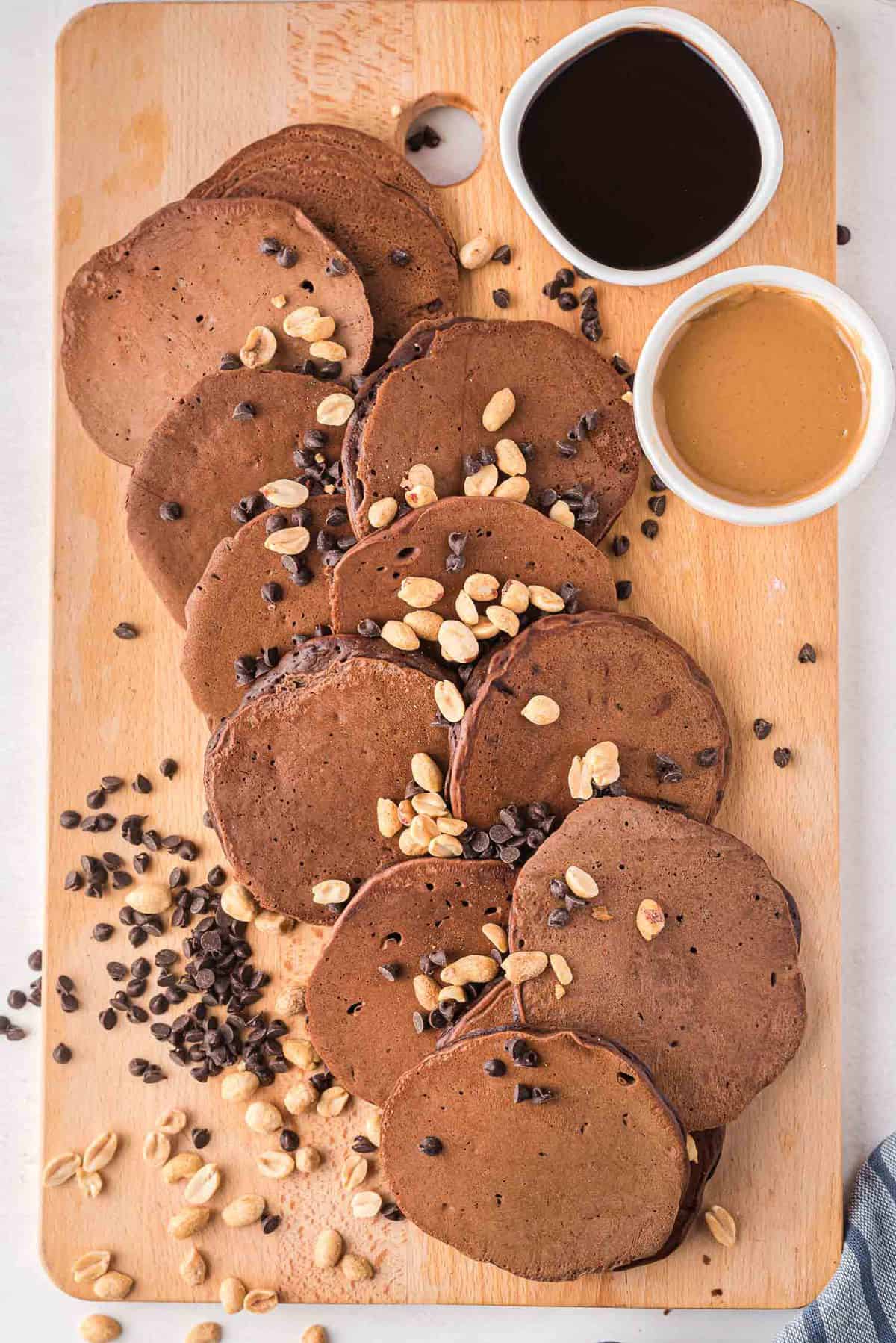 Plato de panqueques de chocolate espolvoreados con cacahuetes y chispas de chocolate.