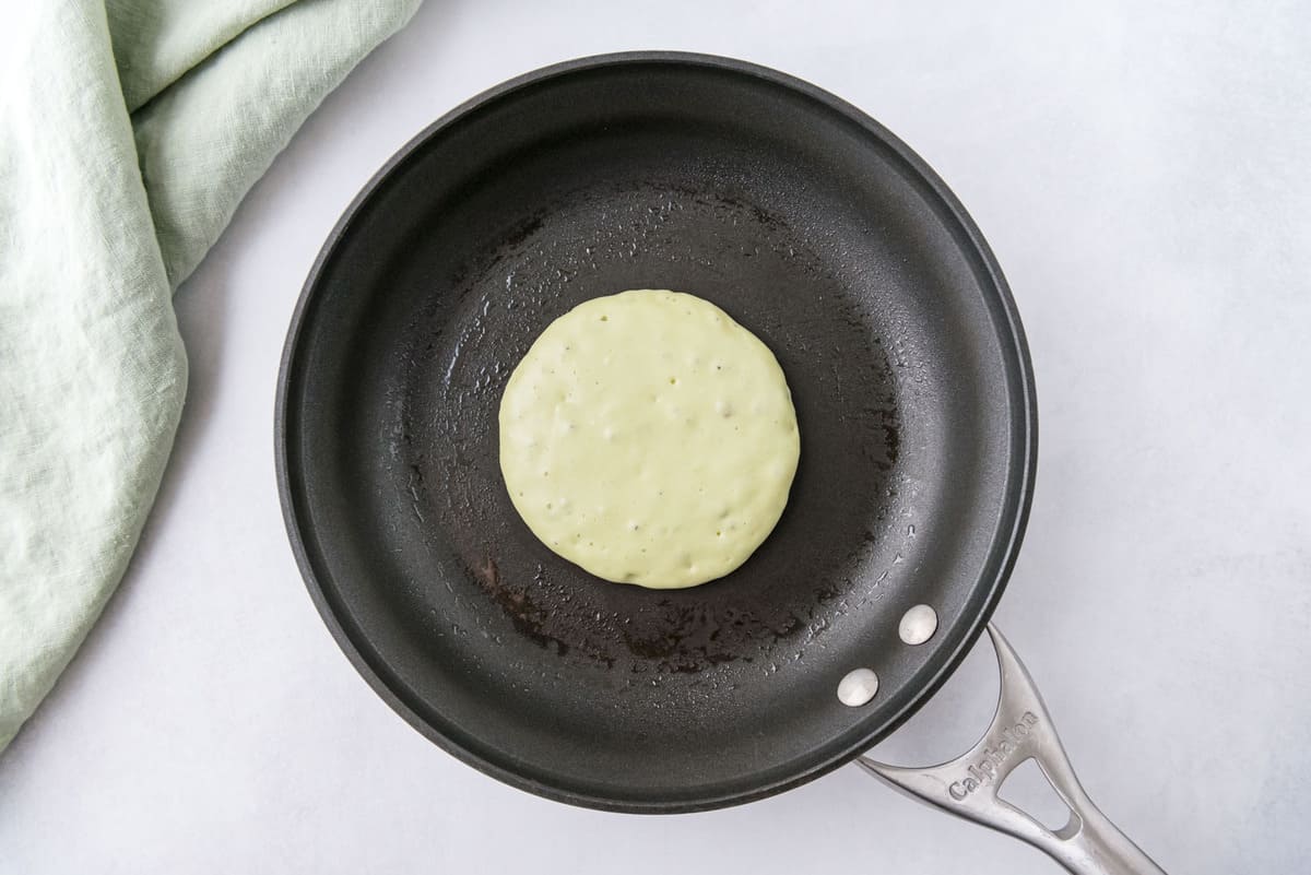 黑色平底锅中未熟的浅绿色煎饼。