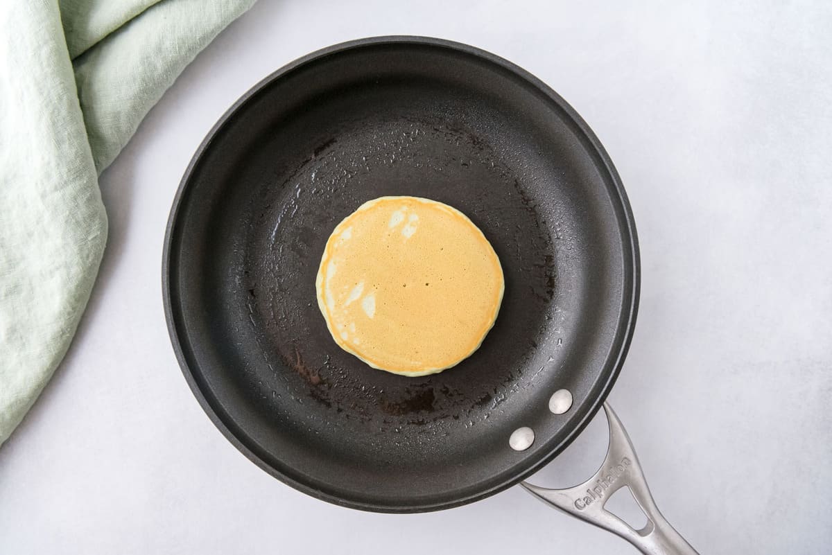 黑色平底锅中煮熟的煎饼。