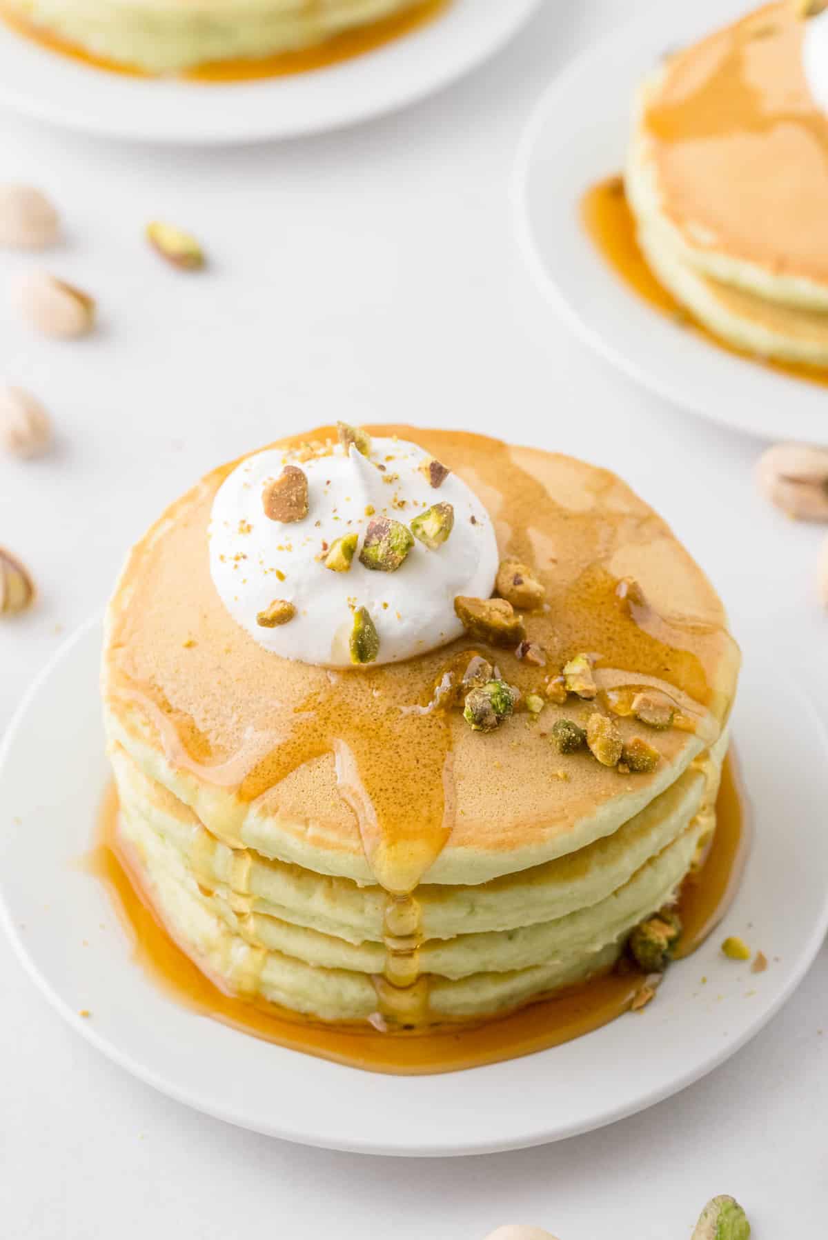 撒上糖浆、鲜奶油和开心果的煎饼。