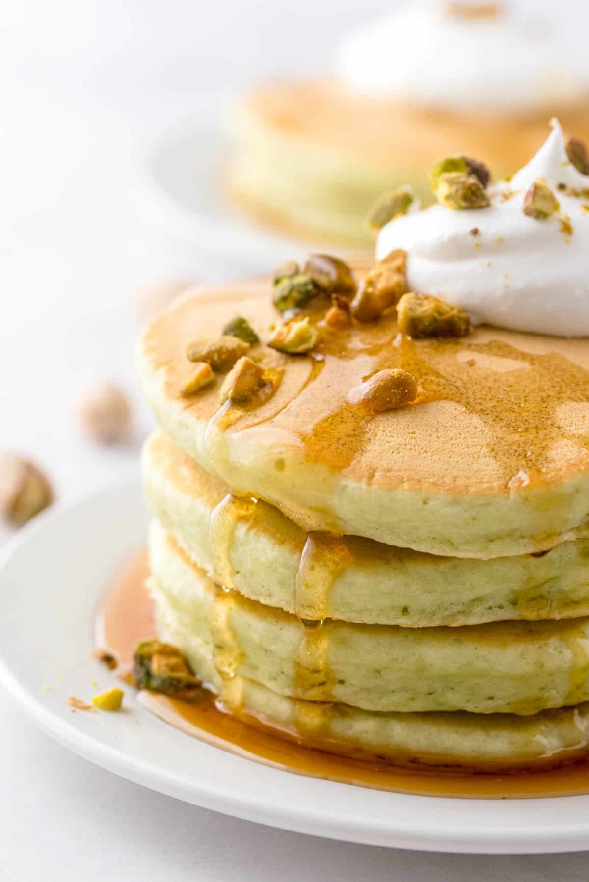 短小轻绿色煎饼，淋上糖浆并撒上开心果。