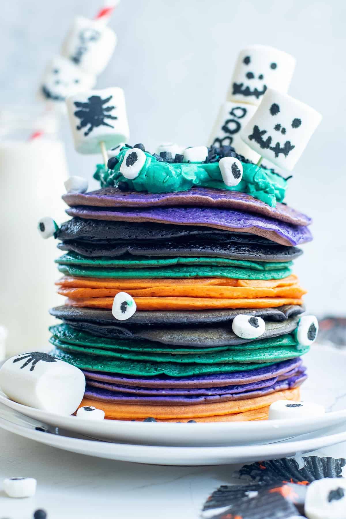 多种颜色的万圣节煎饼叠加，上面装饰了棉花糖。