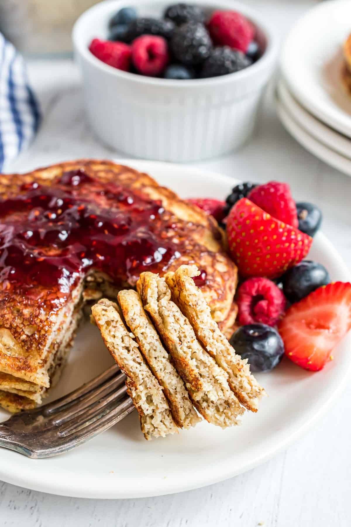 Pancakes on a fork with a stack in the background.